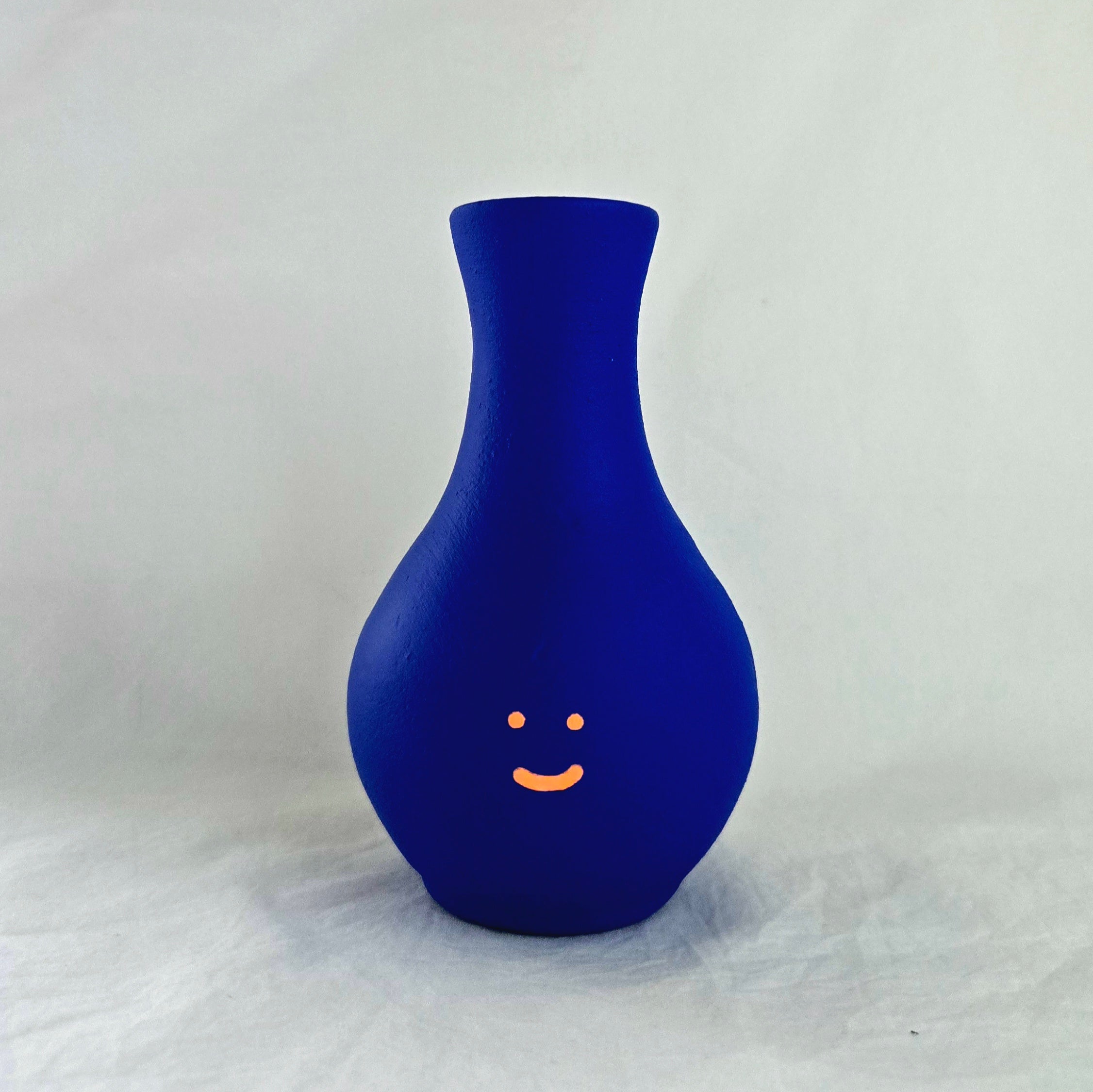 Florero azul en cerámica. Intervenido por cifuentes artista abstracto colombiano titulado HAPPY FLORERO ORANGE, vista frontal